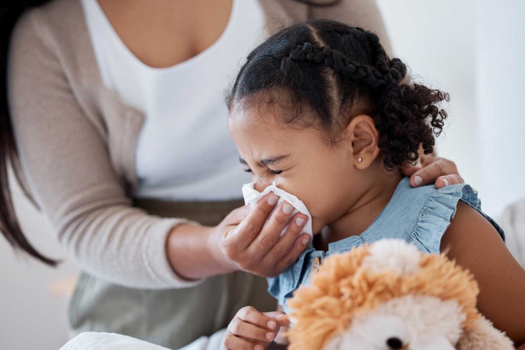 Mother helping young child blow her nose